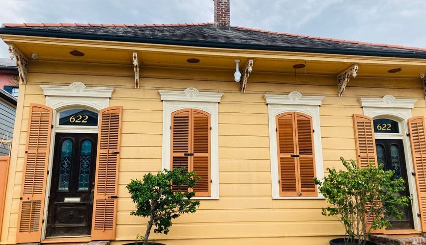 Colorful New Orleans shotgun house with fresh siding and a gabled front porch